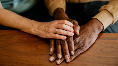 Getty Images Close up of two adults' hands, one on top of the other