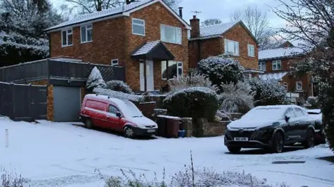 Snowy road and cars and houses in an urban area