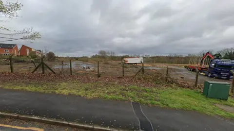 A patch of derelict land viewed from the road nearby