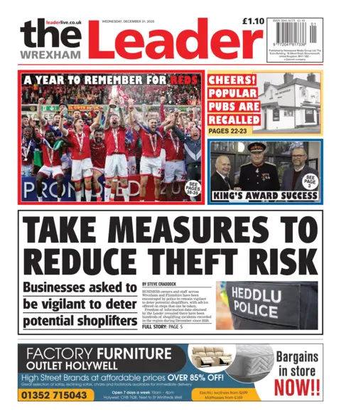 The Wrexham Leader Front page of the Wrexham Leader with the main headline reading: Take measures to reduce theft and risk, and the sub-headline: Businesses asked to be vigilant to deter potential shoplifters, and an image of the back of a police jacket, with the words Heddlu/Police in white text. Above is an image of Wrexham football club celebrating with the headline A year to remember for the reds. Next to that is a black and white image of a house with the headline "Cheers"! Popular pubs are recalled." And under that is a headline reading "King's award success."