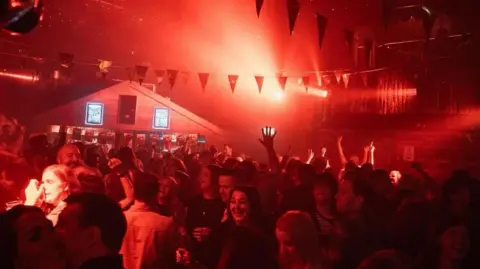 The Shed Interior of nightclub The Shed with a large crowd and bright red lights