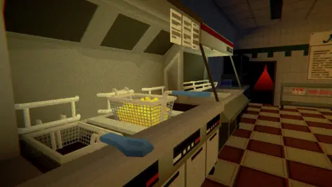 James Muirhead Screenshot from a horror computer game set inside Mac’s Fish Bar, showing a row of metal fryers with baskets of chips under bright heat lamps, blue-handled fryer baskets resting on the counter, red-and-white tiled flooring, and a dark back doorway illuminated by an ominous red light.