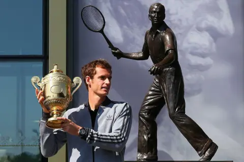 Getty Images Andy Murray of Great Britain poses with the Gentlemen's Singles Trophy next to the Fred Perry statue at Wimbledon on July 8, 2013 in London, England. 