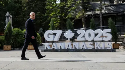 Canadian Prime Minister Mark Carney walks by a large sign for the G7 summit in Kananaskis during the G7 Leaders' Summit in Alberta, Canada