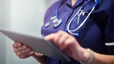 A generic picture of a surgeon or nurse looking at an electronic pad. 