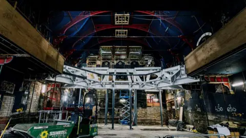 Chesterfield Borough Council Steel girders elevated over a stage area in a large arched hall