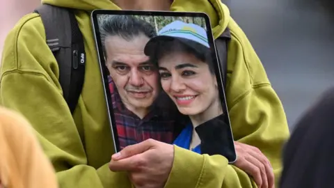 File photo showing a demonstrator holding a picture of Iranian-German Jamshid Sharmahd (L) with his daughter Gazelle Sharmahd (R) during a rally calling for his release in front of the German foreign ministry in Berlin (31 July 2023)