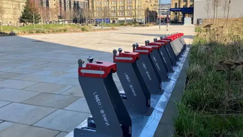 E-bike docking stations in grey and red in the centre of Bradford