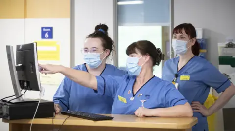 PA Media NHS staff wearing blue tunics