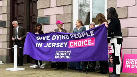 Campaigners in jersey today satnding with a purple banner saying ' Give dying people a chance in Jersey'