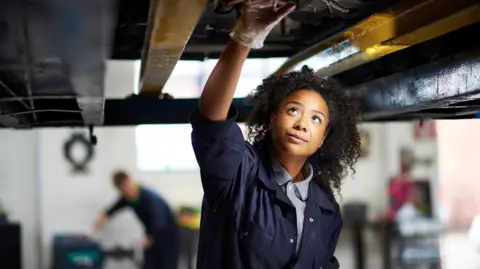 Getty Images Female mechanic moving   connected  the underside of a car