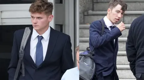 Eddie Mitchell Two young men outside court in blue suits with bags over their shoulder
