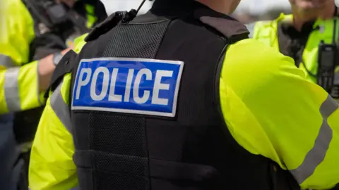 Getty Images A general view picture of a police officer's back, as they wear a hi-vis coat and black jacket that says "police" on the back of it.