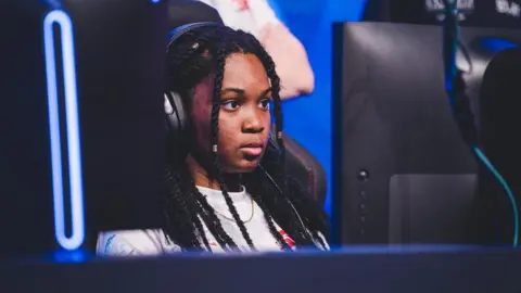 Alanis A young girl with braided hair is staring intently at a computer screen while wearing headphones. 