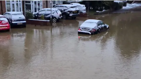 Cars in standing water with snowfall on car roofs
