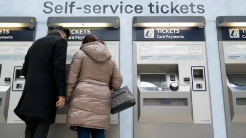 PA Media People using a ticket machine at Waterloo train station in London.