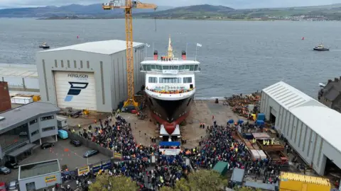 MV Glen Rosa ferry slides down the slipway into the River Clyde with a crowd watching in the shipyard.