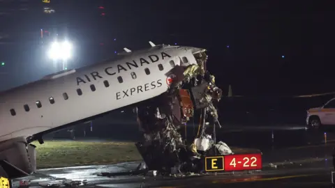 Getty Images An Air Canada plane with damage at the front as it hinges upwards