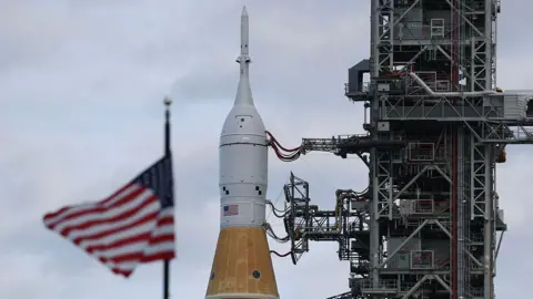 Joe Raedle/Getty Images NASA's Artemis II is rolled from the Vehicle Assembly Building at NASA’s Kennedy Space Center as the American flag sits in the foreground 