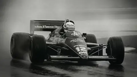 Classic Team Lotus A black and white photo of a racing driver in a F1 car on a track