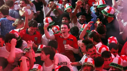 A large group of England football fans celebrating. 