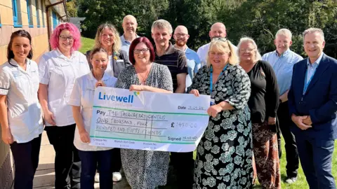 Karen Paget Large cheque being held up in front of a group of smiling people. 