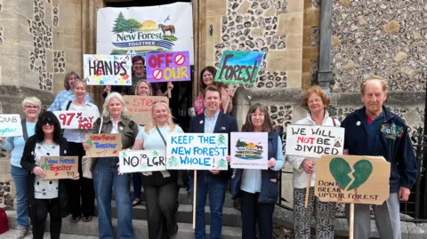 People standing outside Hampshire County Council with banners 