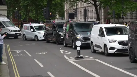 Vans with union jacks and campaign branding line the street around Parliament squate