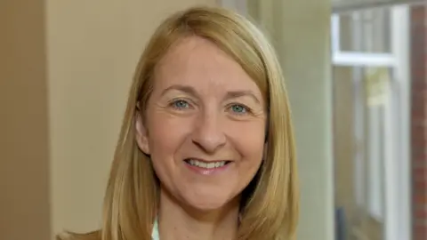 A woman with long, blonde hair smiling at the camera.