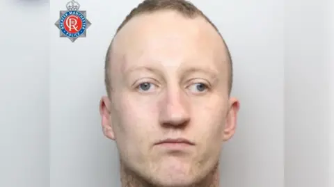 Police mugshot of Adam Thomson, who has close-cropped greying hair which is receding. He has blue eyes which stare impassively towards the camera.