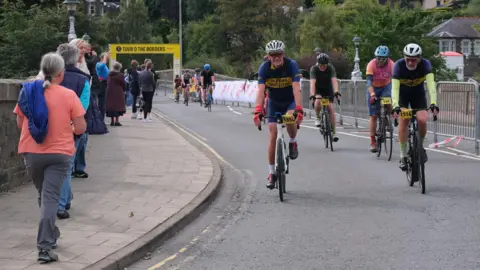 Jim Barton A number of cyclists crossing the finish line in Peebles on the Tour O The Borders - some spectators are lining the route