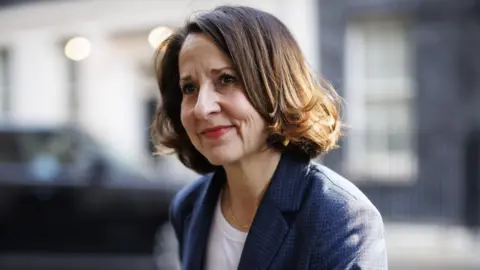 EPA Close up of Liz Kendall. She has a light brown bob, and wears a white t-shirt under a chequered blazer. 