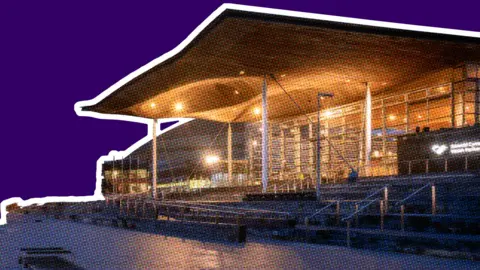 The Senedd building in Cardiff Bay, at night, against a red graphic background