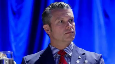 US Secretary of Defense Pete Hegseth wears a blue suit and red tie at a recent prayer breakfast in Washington