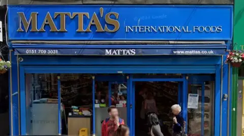 Google A blue shop front with the word Matta's in gold lettering and International Foods in white lettering.