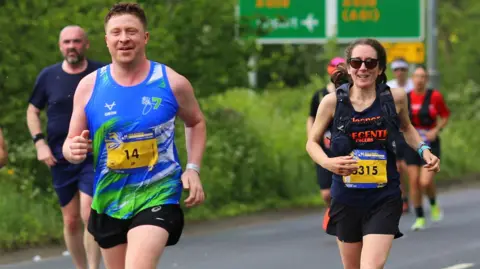 Eleanor Thomson Councillor Eleanor Thomson runs in a black running vest and shorts behind fellow councillor Jonathan Pryor, in a blue running vest and shorts.
