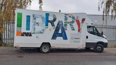 Nottingham City Council A photograph of the mobile library van taken from the side, parked at the edge of the road