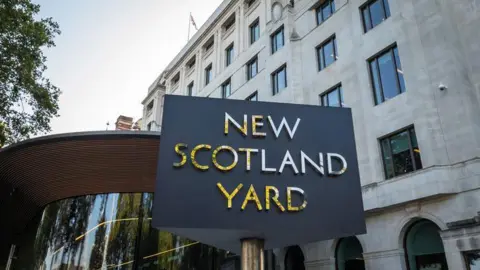 View of Metropolitan Police headquarters with the "New Scotland Yard" rotating sign seen in the foreground.