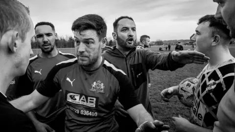 John Bolloten A black and white photo of men in football shirts who appear to be in a disagreement