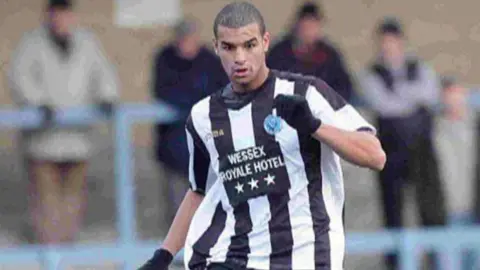 A footballer wearing a black and white football shirt