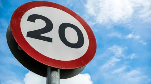 A round, red and white road sign showing the 20mph speed limit