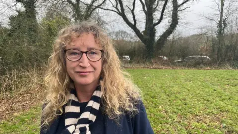 Liberal Democrat leader Caroline Leaver in a striped scarf on a patch of grass.