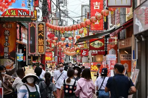 Getty Images Crowds of people walk down a street in the Chinatown section of Yokohama