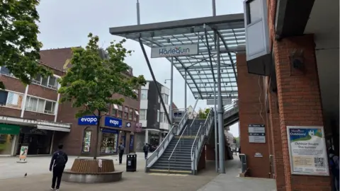 Harlequin Theatre and Cinema, Redhill town centre. Steps lead up to the theatre's entrance, with a small tree with a circular bench in front of them. 