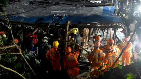 Reuters Rescue workers are seen moving through wreckage after a huge billboard blew down in sudden storm in Mumbai, India.