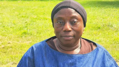 Makagbeh Princess Sesay Makagbeh sits in a park smiling.