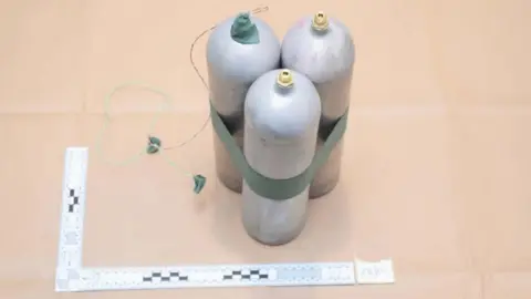 MET POLICE Three metal canisters, tied together with green tape and with what appears to be a wire hanging off the top of one, in a police evidence photo 