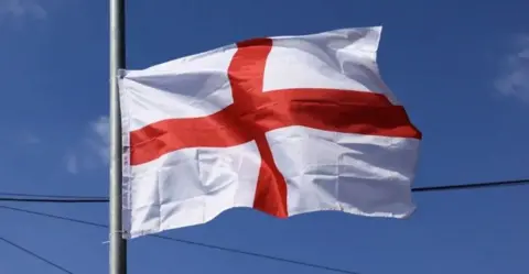 A St George's Cross flag flying against a blue sky