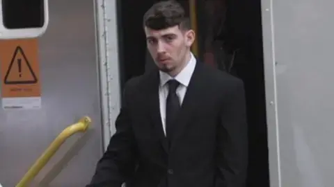 Kian Bateman arriving at Cardiff Crown Court, dressed in a dark suit and tie