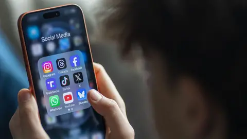 A stock image showing looking at the social media application menu, which includes apps for Instagram, Facebook and TikTok, on his smartphone. 
